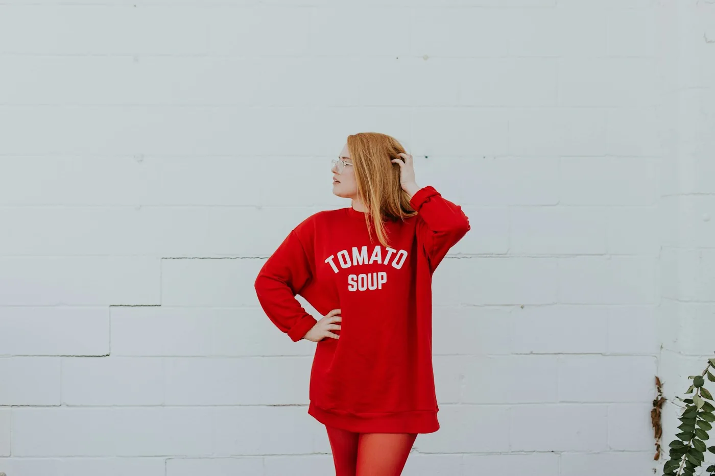 Woman wearing a red sweatshirt dress beside a white wall