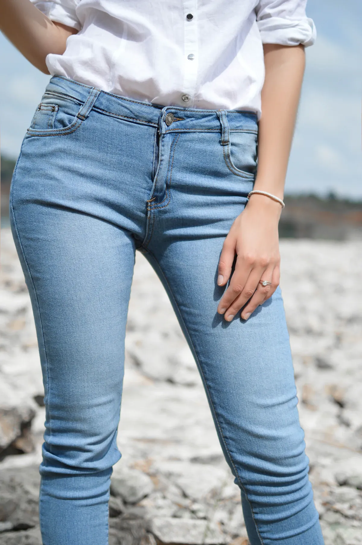 A close view of a white shirt tucked into blue jeans outdoors