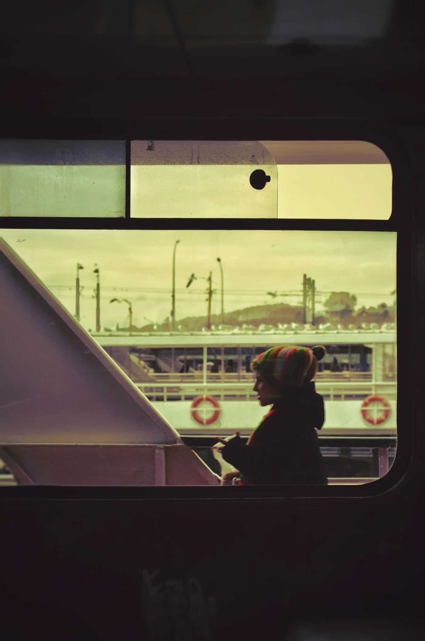 A seated passenger silhouetted beside a yellow-lit train window.