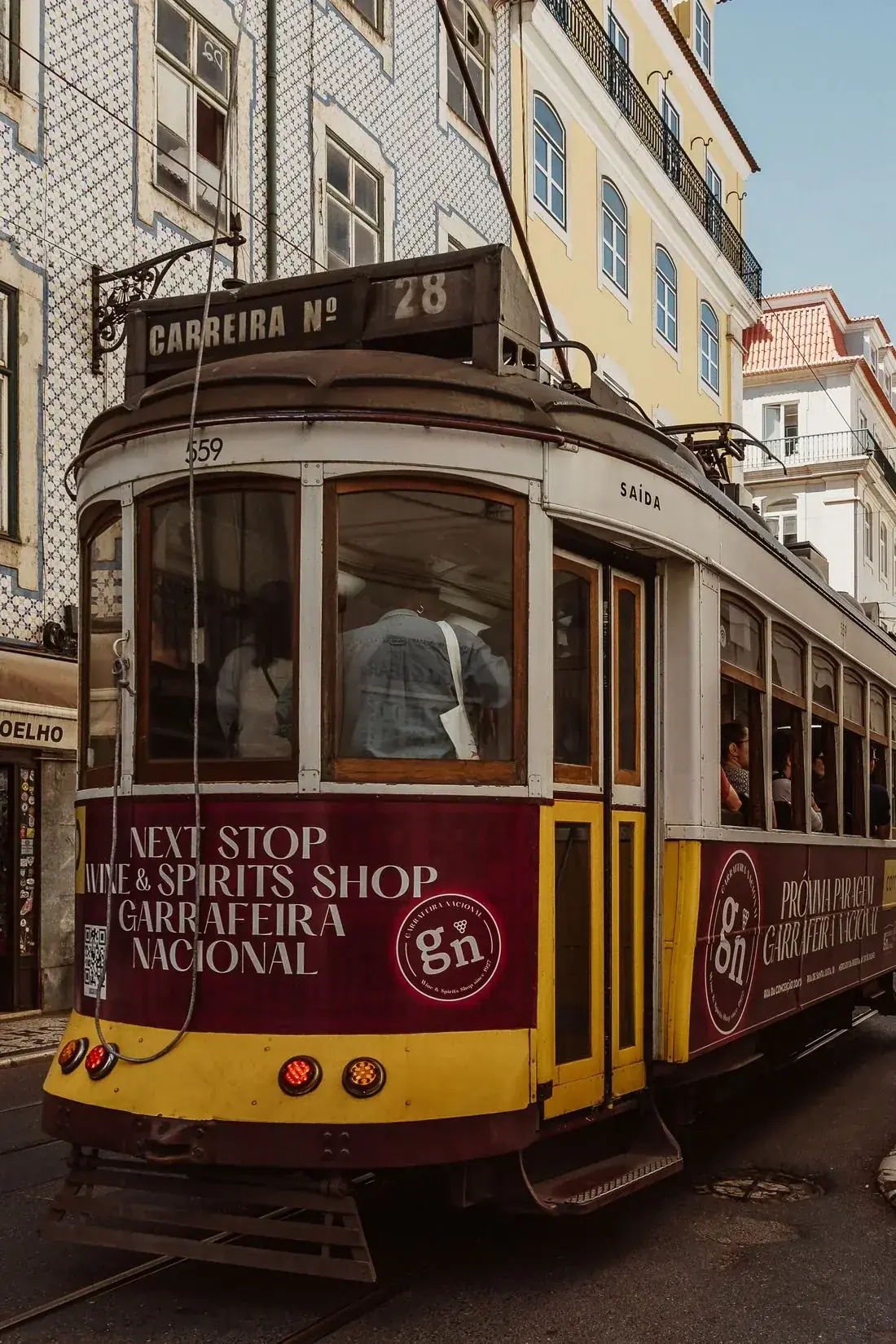 A yellow and red tram on a narrow city street.