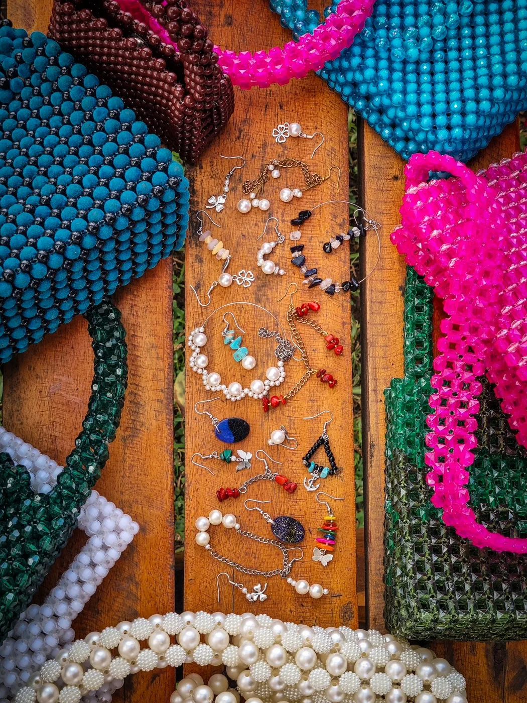 Brightly coloured beaded bags and jewellery displayed on a wooden surface.