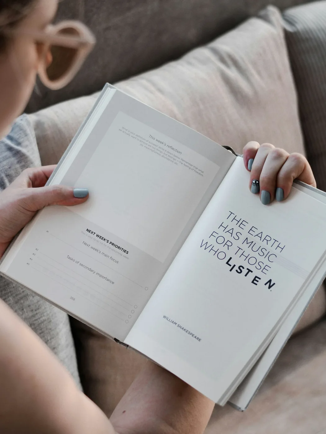 An open book held during a reading pause above pale fabric.