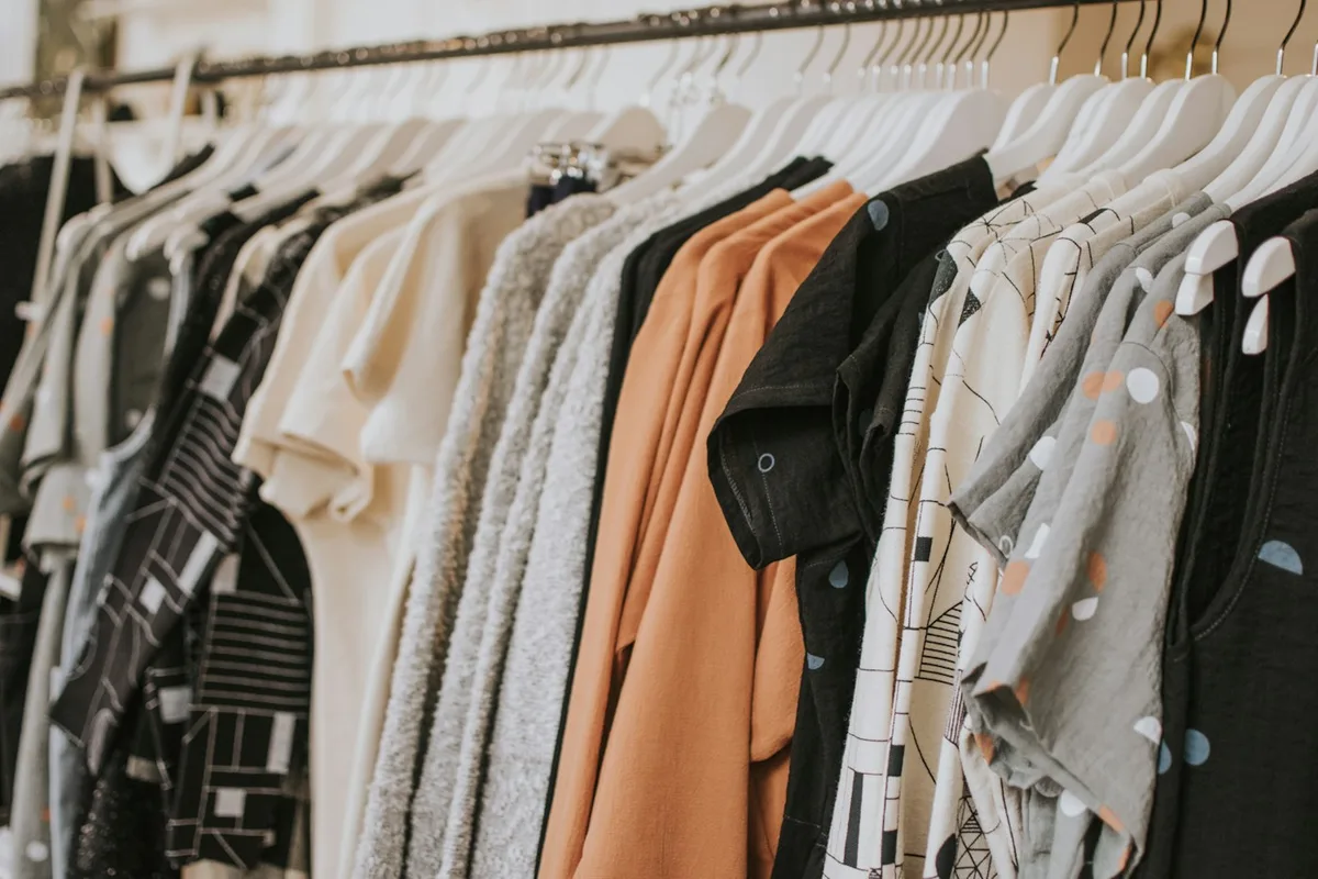 Pale, dark and warm-coloured garments arranged closely on a rail.