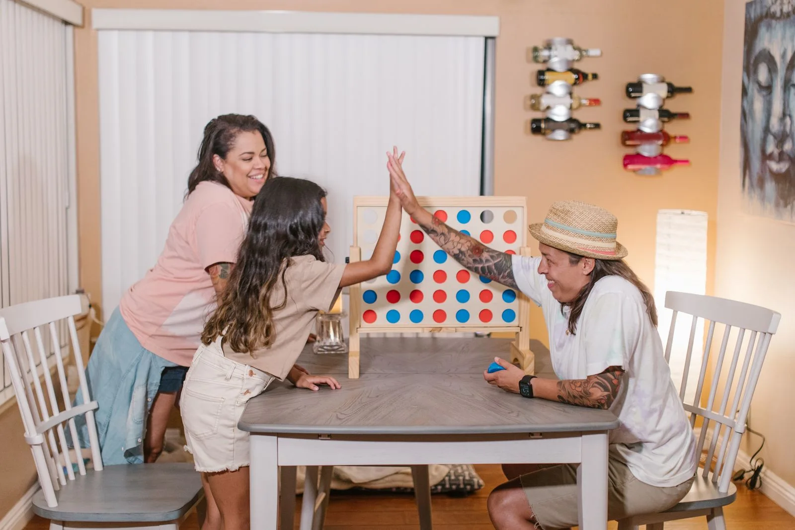 Three people gathered around a colourful upright game board on a table.