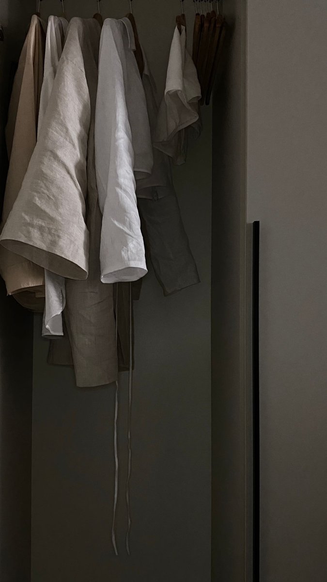 Pale garments hanging in a softly lit wardrobe.