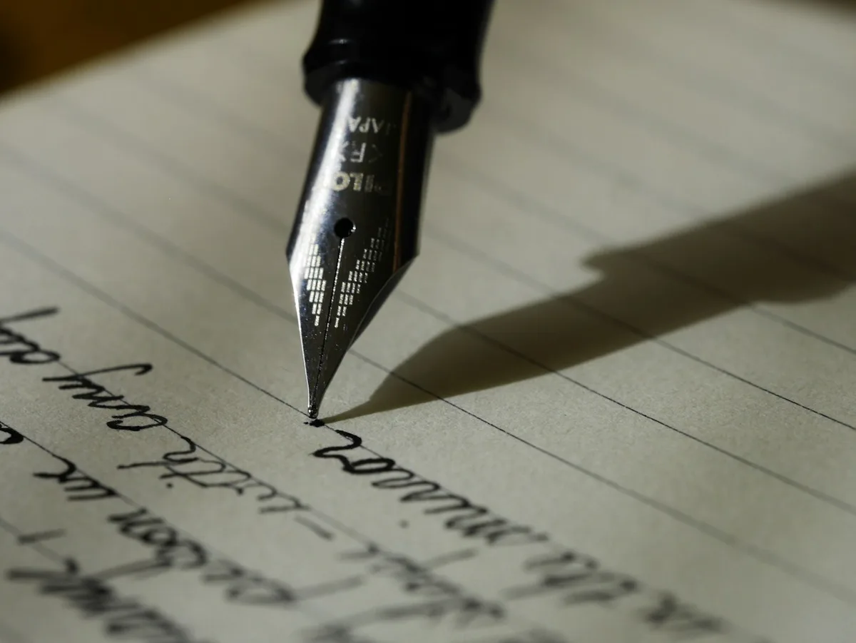 Fountain pen poised above an open notebook