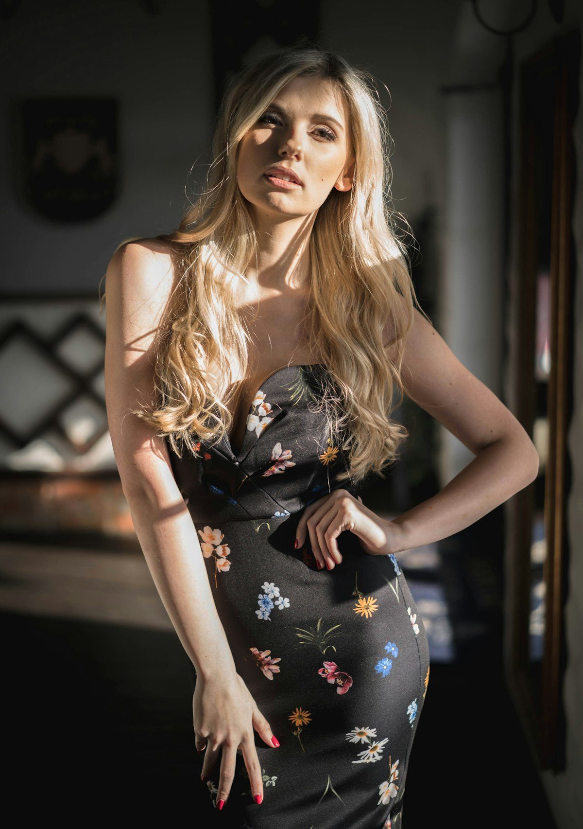 A woman wearing a dark floral dress in an indoor setting.