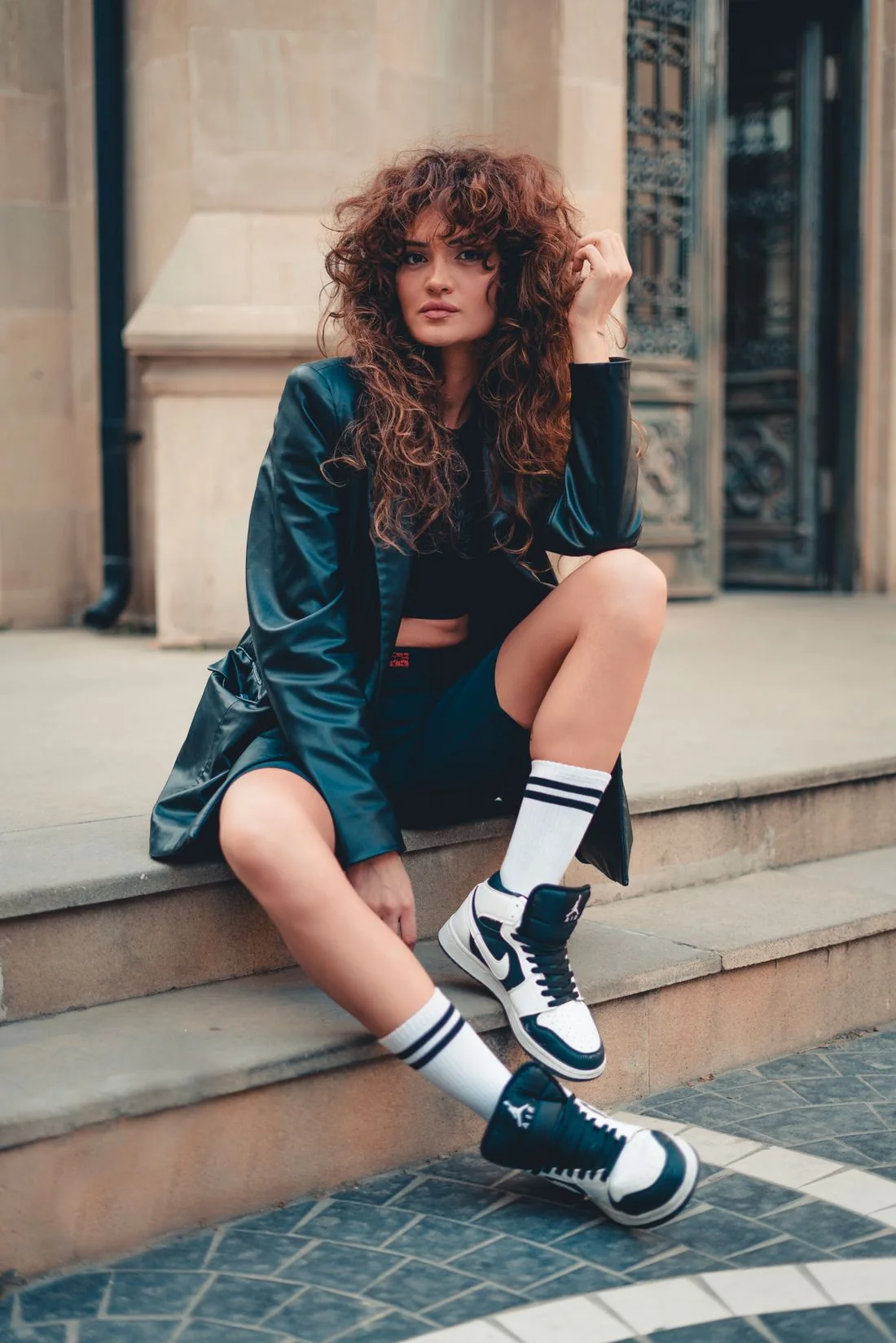 A person seated on steps while fastening dark lace-up shoes.